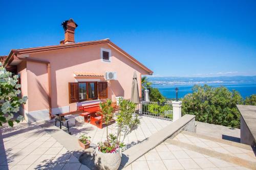 een klein roze huis met uitzicht op de oceaan bij Apartments Jasminka Lovran in Lovran