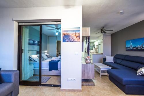 ein Wohnzimmer mit einem blauen Sofa und einem Bett in der Unterkunft Trisol Seaviews in Benidorm