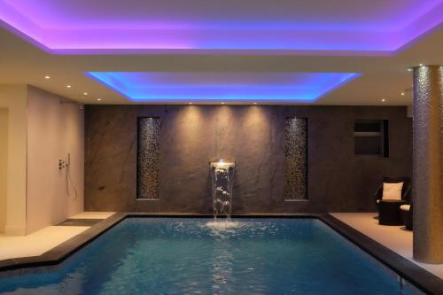 a swimming pool with a fountain in a hotel room at Les Criquets Hôtel & Spa in Blanquefort
