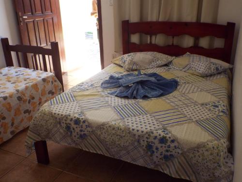 a bed with a comforter and a shirt on it at Pousada Marambaia in Caraguatatuba