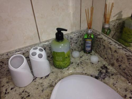 Un mostrador de baño con un inodoro y productos de limpieza encima. en Apartamento na Praia Grande, en Praia Grande