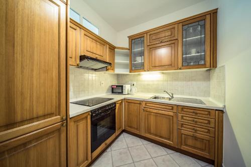 a kitchen with wooden cabinets and a sink at St. George Apartments in Prague