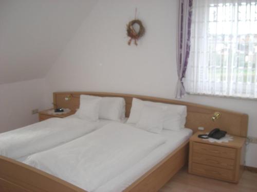 a bed with white sheets and pillows in a bedroom at Pension Beer in Mähring