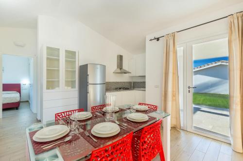 a dining room with a table and chairs and a kitchen at Ville D'Ogliastra in Cardedu