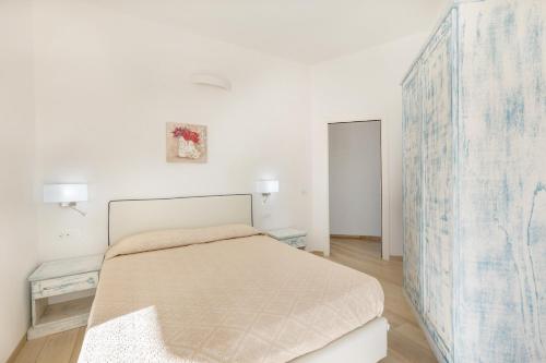 a white bedroom with a bed and two tables at Ville D'Ogliastra in Cardedu