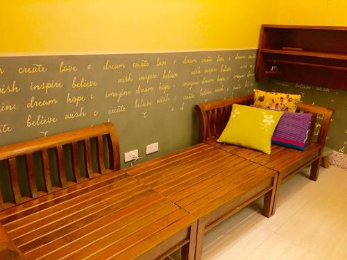 a bench with two pillows on it in a room at Home & Teak Homestay in Jinning