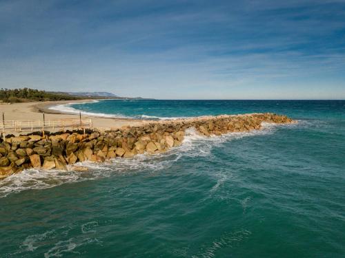 a beach with a pier and the ocean at Ville D'Ogliastra in Cardedu