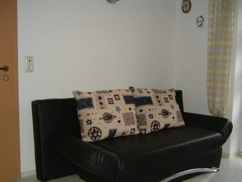 a black leather couch with a pillow on it at Pension Beer in Mähring