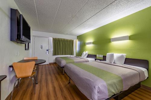 シンシナティにあるDays Inn by Wyndham Cincinnati I-71のベッド2台、テーブルと椅子が備わるホテルルームです。