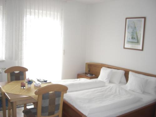 a bedroom with a bed and a table and a window at Pension Beer in Mähring