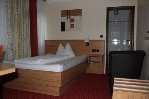 a bedroom with a bed and a desk and a chair at Hotel garni Fuchs in Eichstätt