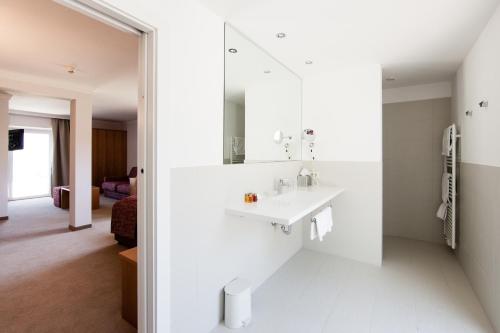 a white bathroom with a sink and a mirror at Hotel MARIA THERESIA adults-only in Lagundo