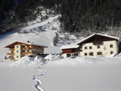 a snow covered building with a trail in the snow at Alfaierhof-Bergheimat in Gschnitz