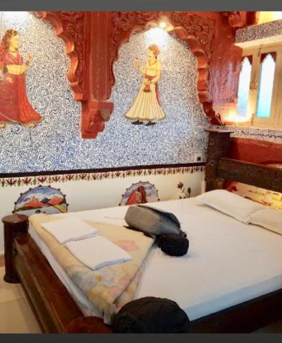 a bed in a bedroom with a wall with a mural at The Blue House in Jodhpur