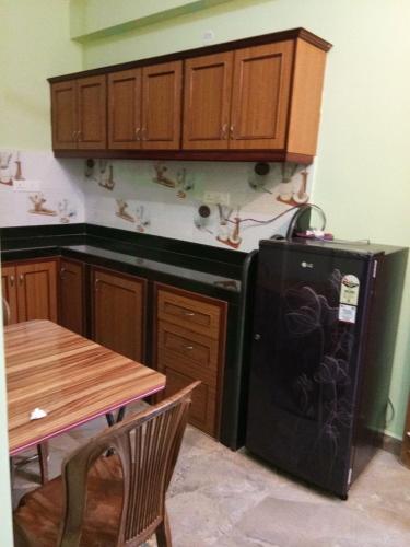 a kitchen with a black refrigerator and wooden cabinets at shirley's guest house in Majorda