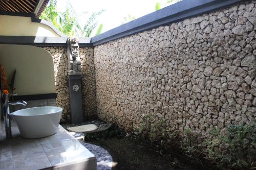 a bathroom with a bath tub next to a stone wall at Bali Gecko Homestay in Pemuteran