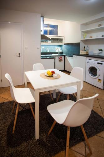 a kitchen with a white table and white chairs at Haas Apartments Stojanova with Parking in Brno