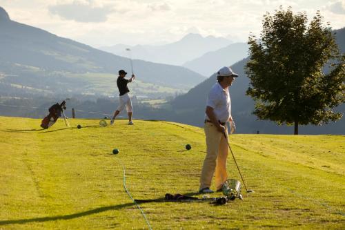 two men are playing golf on a hill at Hotel Garni Tirol in Walchsee