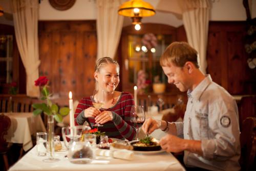 a man and woman sitting at a table eating food at Hotel Garni Tirol in Walchsee