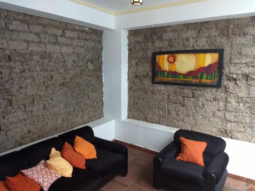 una sala de estar con 2 sofás negros y una pintura en Hotel Residencial España en Salta