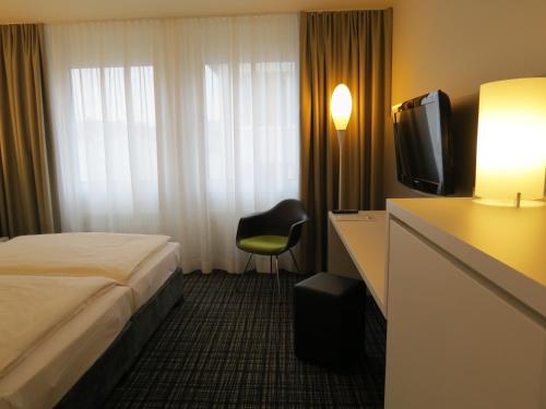 a hotel room with a bed and a television at Comfor Hotel Ulm City in Ulm