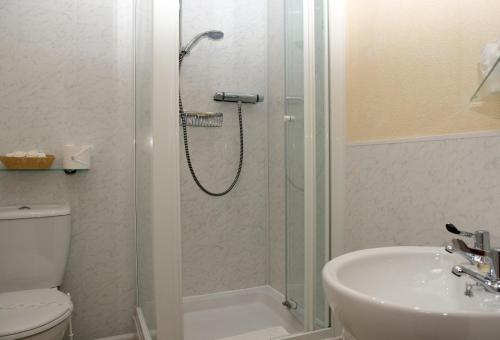 a bathroom with a shower and a toilet and a sink at The Cumberland in Llandudno