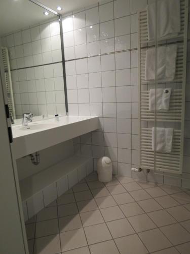 a bathroom with a sink and a tub and a mirror at Comfor Hotel Ulm City in Ulm
