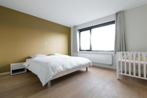 a bedroom with a white bed and a window at Sky & Sand 2 - Free parking - Free bikes - EVcharging in Bruges