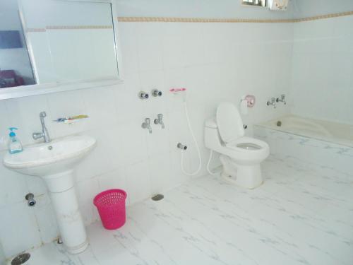 a white bathroom with a toilet and a sink at Hotel Star International in Rājshāhi