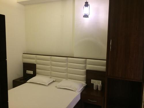 a bed with two pillows and a light above it at Lotus Grand Akm in Kālka