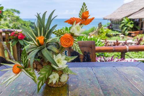 a vase with flowers on top of a wooden table at Milo's Home in Jimbaran