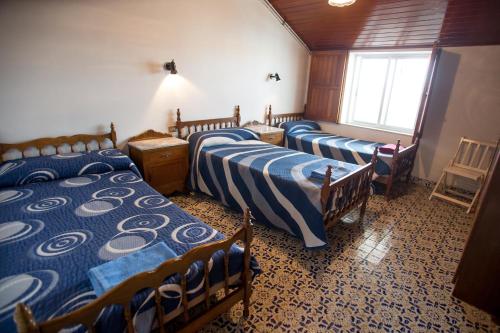 a room with three beds and a window at Albergue Turístico Silleda in Silleda