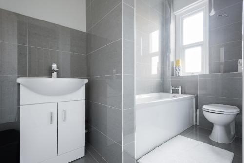 La salle de bains est pourvue d'un lavabo blanc et de toilettes. dans l'établissement The Euston St Pancras Apartments, à Londres