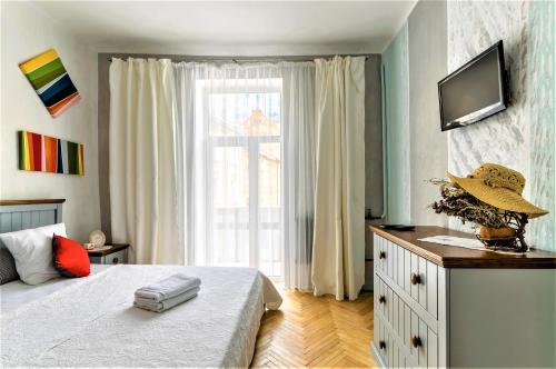 a bedroom with a bed and a television and a window at Izuminka v Centre Goroda in Lviv