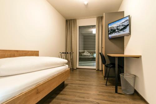 a hotel room with a bed and a desk and a tv at Appartements Ausblick in Sankt Gallenkirch