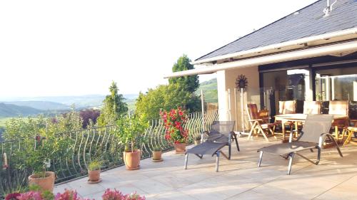 eine Terrasse mit Stühlen, einem Tisch und Pflanzen in der Unterkunft Gästehaus Sproß in Veldenz
