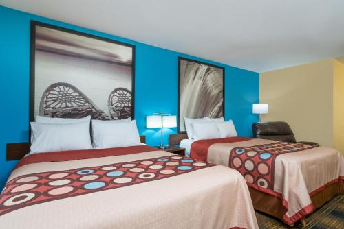 two beds in a hotel room with blue walls at Super 8 by Wyndham Rochester Mayo Clinic Area in Rochester