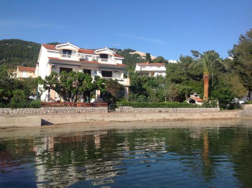 a large white house next to a body of water at Apartment One in Rab