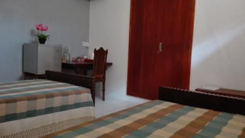 a bedroom with two beds and a dresser and a desk at Crescent N Cocoon in Ambalangoda