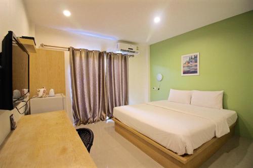 a bedroom with a white bed and a green wall at Green Apple Villa in Sattahip