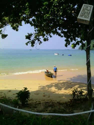 a man standing on a beach with a boat at Baan Suan Kayoo 2 Buffalo Bay Aow Khao Kwai in Ko Phayam