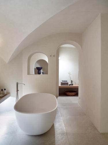 a white bath tub in a bathroom with an archway at Villa Bordeaux in Fira