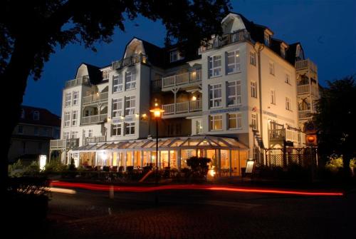 a large white building with a store in front of it at Am Weststrand Aparthotel Kühlungsborn in Kühlungsborn