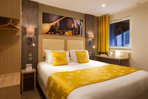 ein Hotelzimmer mit einem großen Bett mit gelben Kissen in der Unterkunft Comfort Hotel Orléans Olivet Provinces in Olivet
