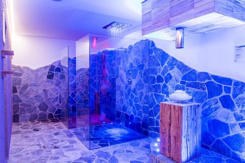 y baño con ducha y pared de azulejos azules. en Hotel Regglbergerhof, en Nova Ponente