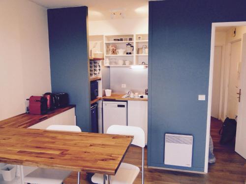 a kitchen with a table and chairs and a blue wall at les pieds dans l'eau in Wimereux