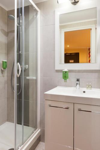 une salle de bain avec un lavabo blanc et une douche dans l'établissement Comfort Hotel Orléans Olivet Provinces, à Olivet