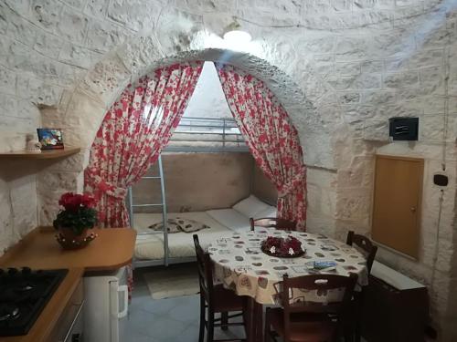 eine Küche mit einem Tisch und ein Zimmer mit einem Bett in der Unterkunft Trulli Manuela in Locorotondo