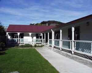a house with a porch and a grass yard at South Sea Hotel - Stewart Island in Half-moon Bay