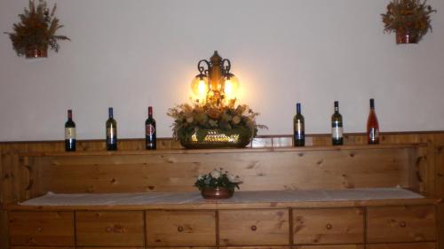 a shelf with wine bottles on it with a light at Hotel Villa Ines in Borca di Cadore